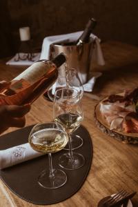Versamento di vino bianco in calici di cristallo durante una degustazione, accompagnato da salumi e atmosfera elegante e raffinata.
