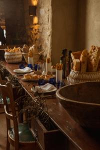 Tavola rustica apparecchiata con pane artigianale, cestini in vimini, olio d'oliva e calici blu in un ambiente in pietra dal fascino mediterraneo.