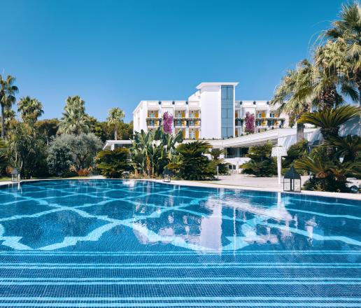 Hotel di lusso con piscina panoramica, immerso nel verde tropicale, con eleganti architetture bianche e un’atmosfera esclusiva.