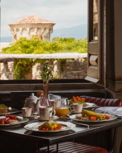 Gourmetfrühstück, das in elegantem Ambiente am Tisch serviert wird, mit süßen und herzhaften Speisen und einem herrlichen Blick auf die Landschaft mit einem steinernen Turm.