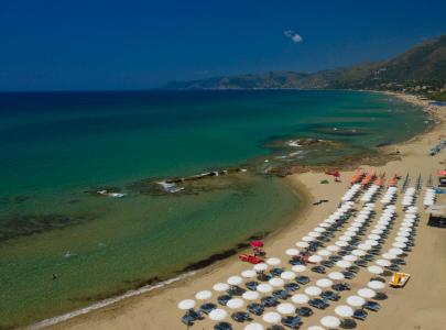 Spiaggia di sabbia dorata con ombrelloni bianchi e mare cristallino turchese.