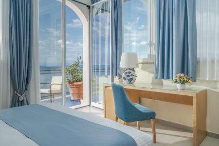 Helles Zimmer mit Meerblick, hellblauen Möbeln und Zugang zum Balkon.